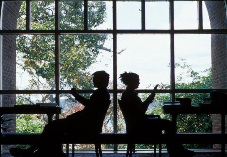 学生们坐在图书馆里，窗外的背景映衬出他们的剪影