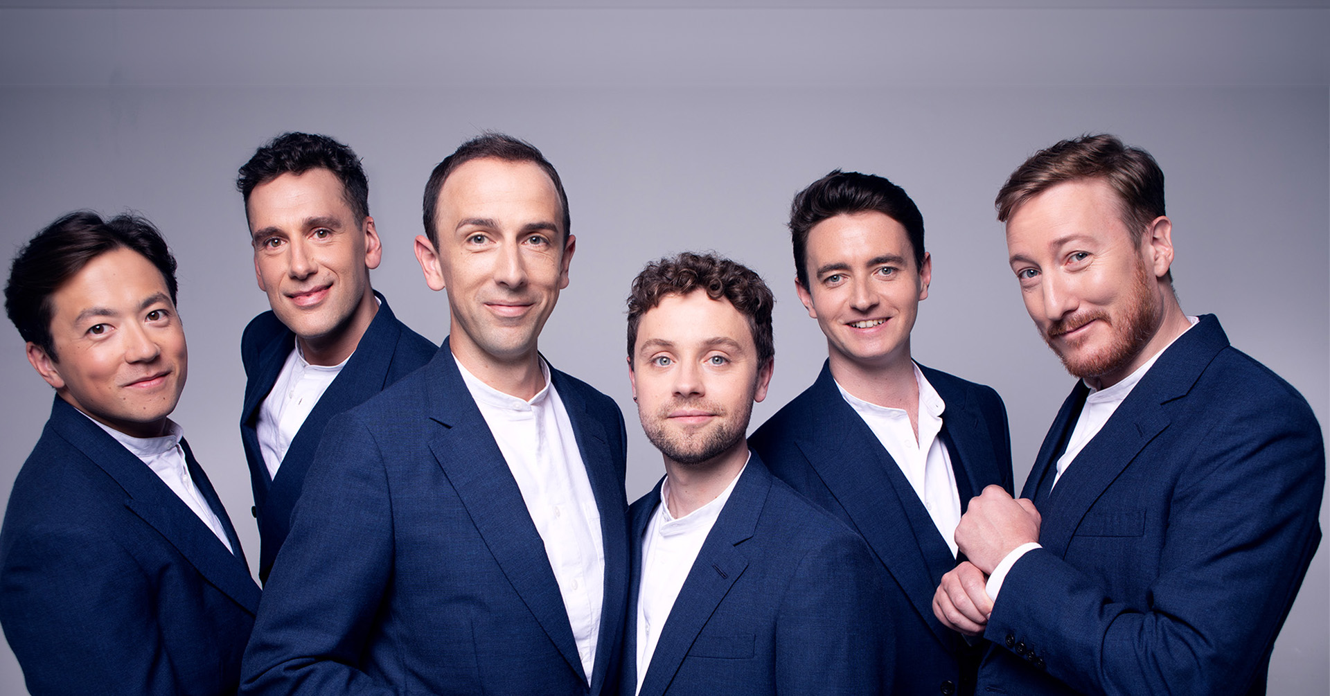 Image of 6 men dressed in suits on a grey background