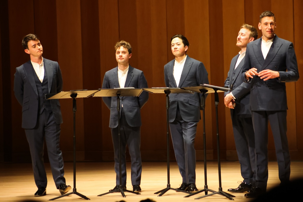 5个穿着西装的男人站在舞台上