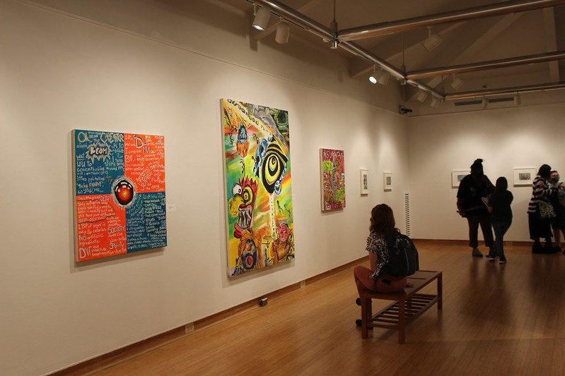 Boyden Gallery displaying pieces from the Metropolis Scrolling Exhibit while visitors look at vibrant art on the walls