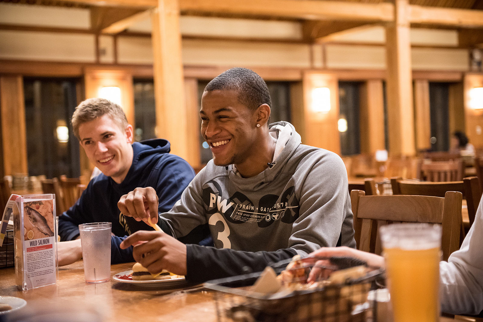 Two students laughing as they enjoy their meal in the great room