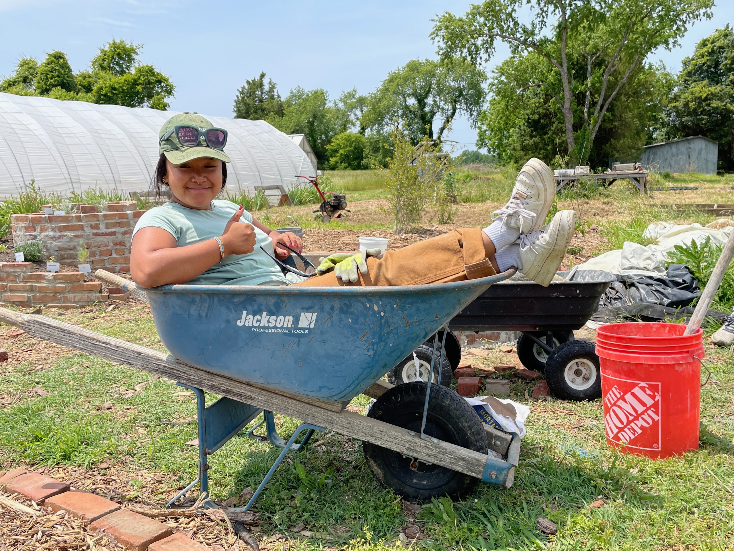 A student intern takes a quick break from her internship duties at the Kate Farm to snap a picture in a wheelbarrow