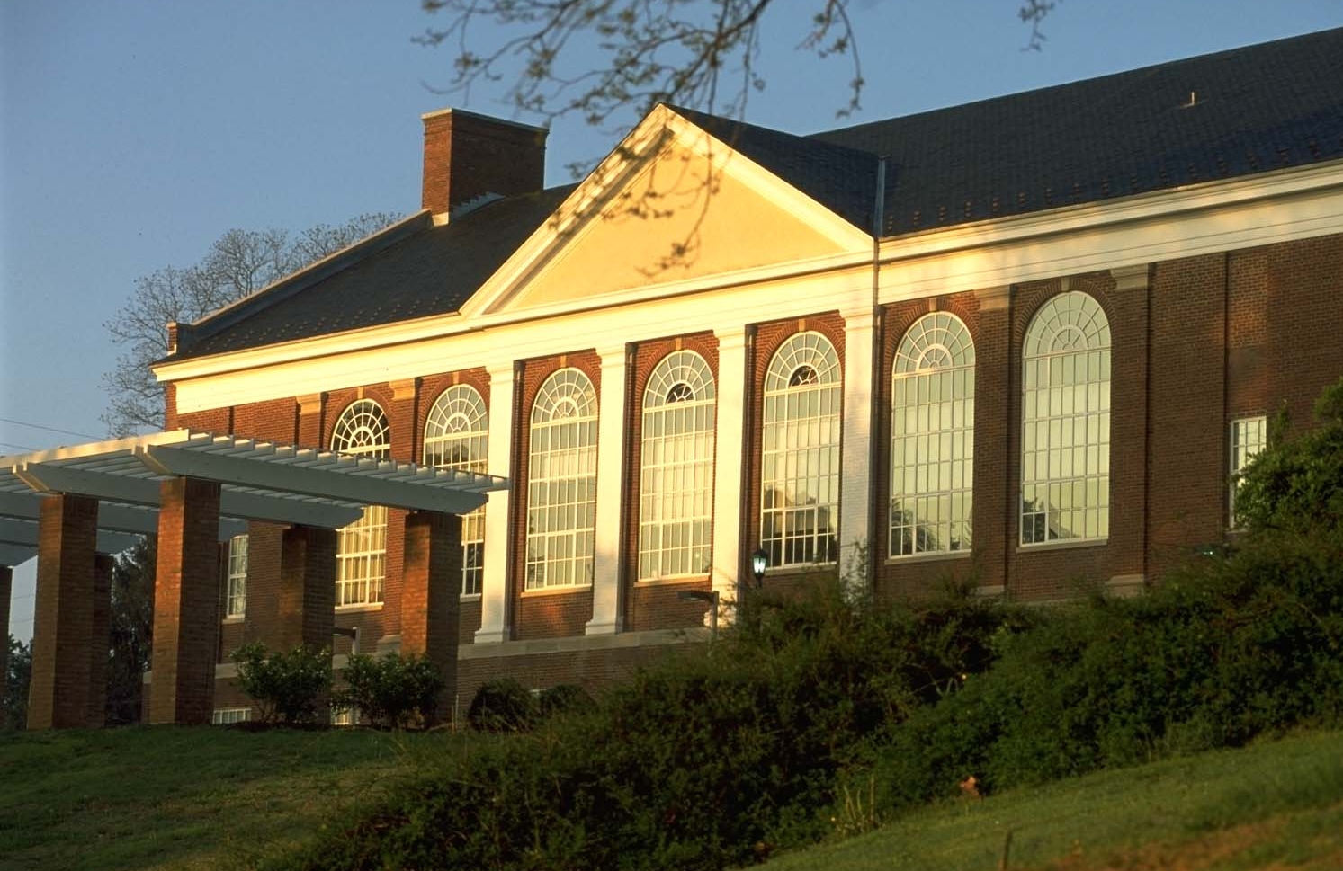 A historic brick building with white columns surrounded by grass.