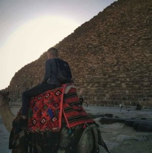 Student on a camel in front of a pyramid in Giza, Egypt
