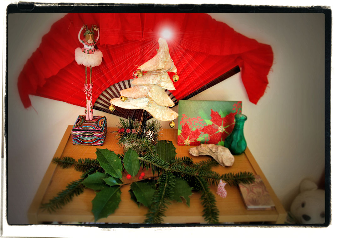 Merideth Taylor - Holiday display with red fan, dancer figurine, tree sculpture, card, and pine and holly garland