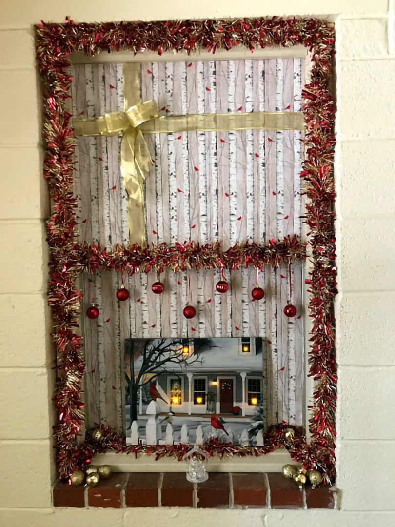 Brenda Rodgers - Holiday window display with frilled trim, ornaments, and wrapping paper bow to look like a gift wrapped package