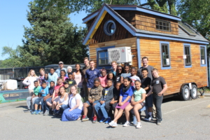 a group of students and children pose in front of the smcm tiny house
