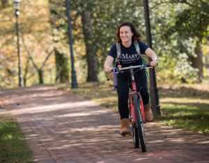 Student riding bike on brick path